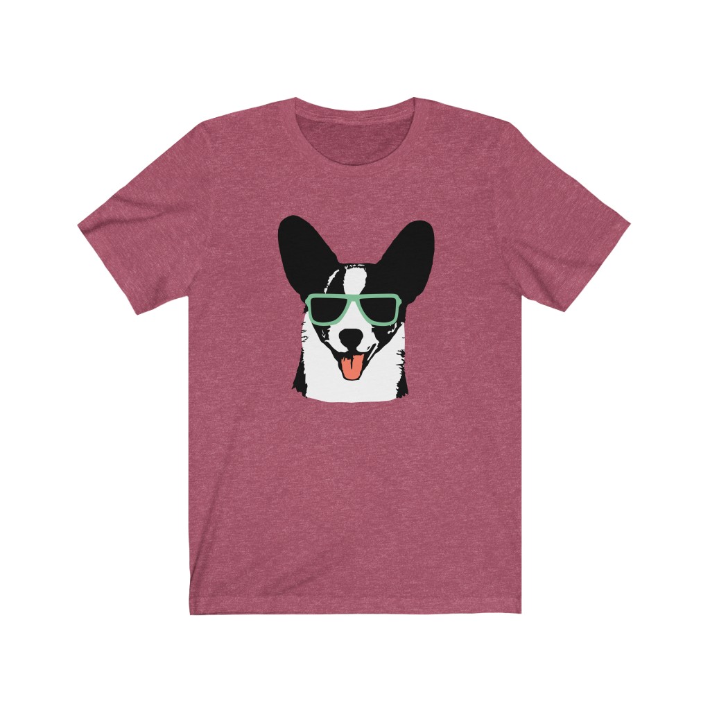 An original Cardi Hardy short sleeve tshirt. Black raspberry-colored tee with Cardi Hardy logo, a Cardigan corgi wearing sunglasses and sticking his tongue out